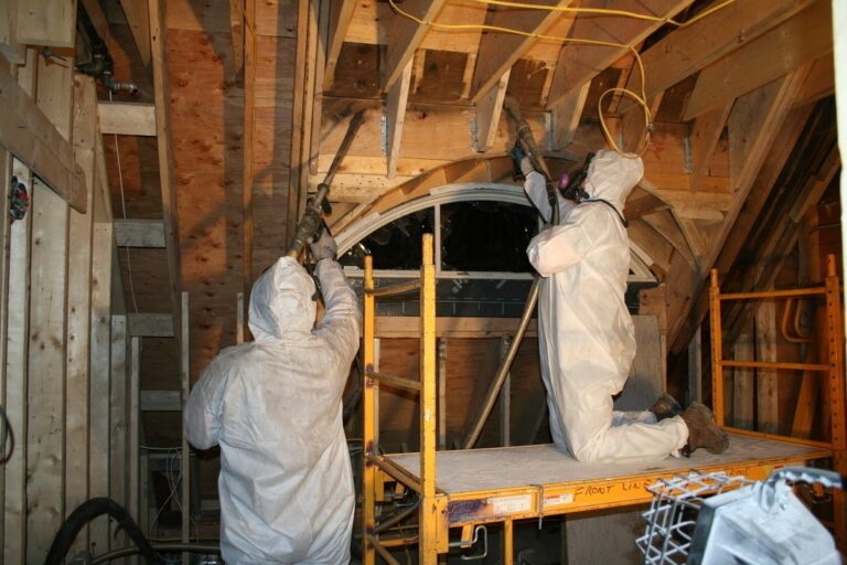Workers inside an attic with exposed framing